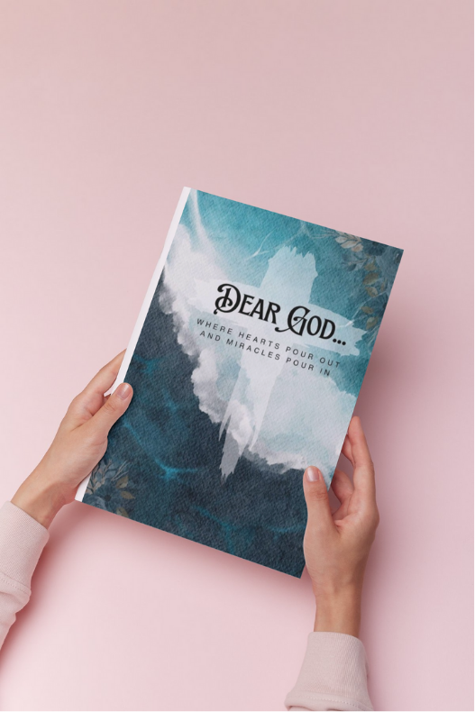 Hands hold a journal titled "Dear God: Where Hearts Pour Out and Miracles Pour In", featuring a calming blue watercolor design against a soft pink background, ideal for prayer and reflection.